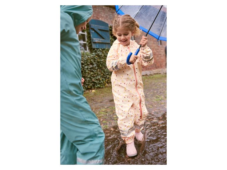 Dieťa v nepremokavom oblečení skáče do kaluže.