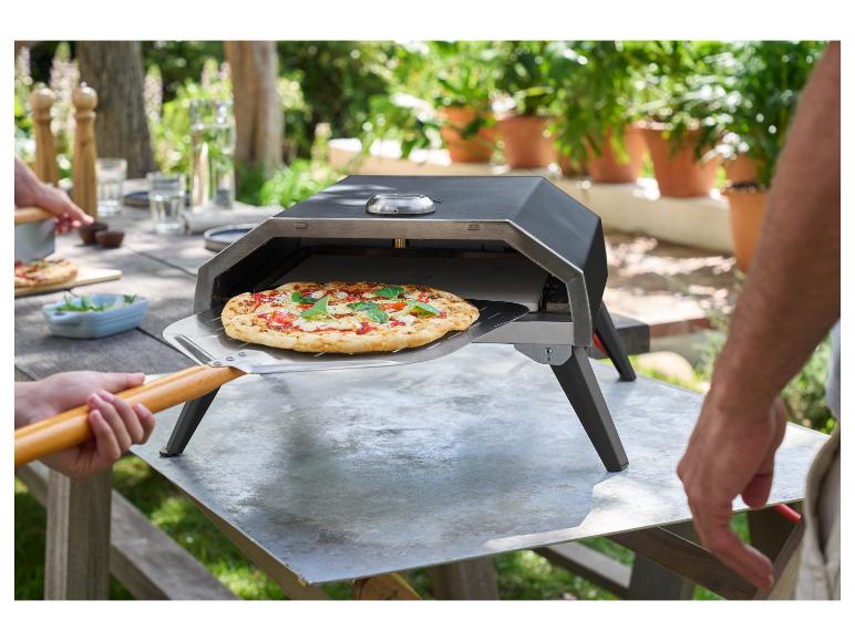 Osoba vyberá pizzu z vonkajšej pece na pizzu pomocou lopaty na pizzu.