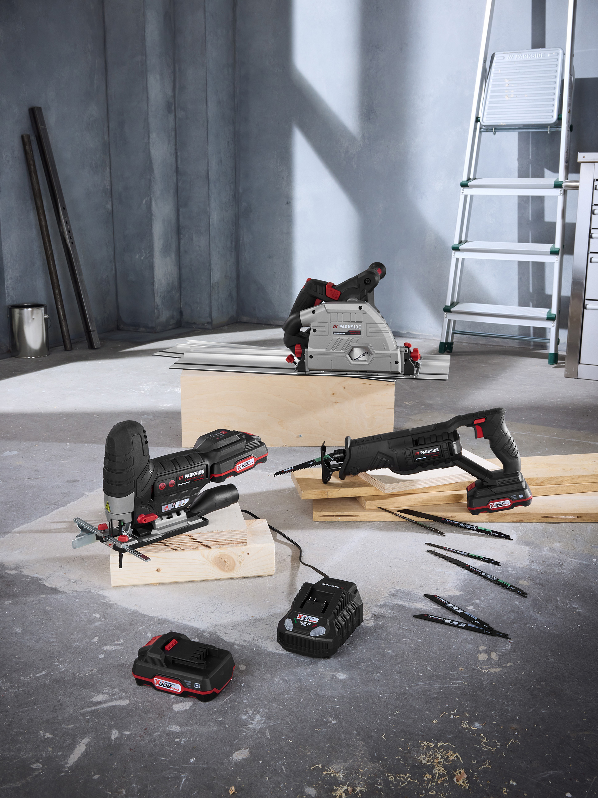 Elektrické náradie Parkside: ponorná píla, priamočiara píla a chvostová píla s batériami a príslušenstvom v dielni.