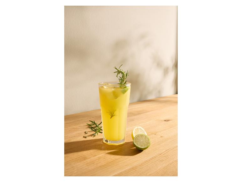 Pohár limonády s rozmarínom a limetkou na drevenom stole.