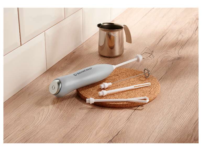 Penič na mlieko Silvercrest s metličkami a džbánom na drevenom pulte.