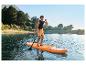 Muž pádluje na paddleboarde na jazere obklopenom stromami a horami.