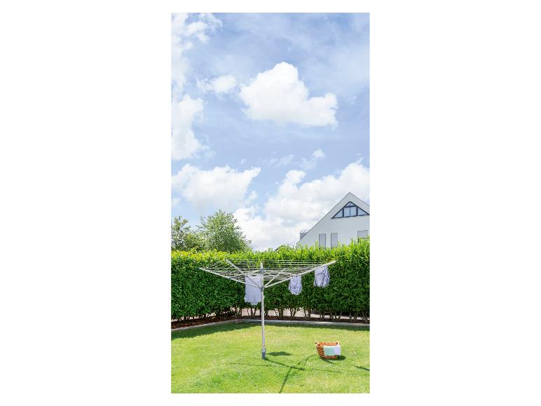 Otočný sušiak na bielizeň so sušiacou sa bielizňou v slnečnej záhrade.