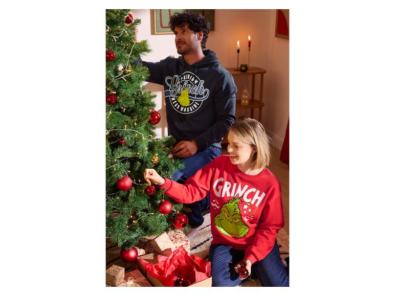 Pár zdobí vianočný stromček v mikinách s motívom Grinch.