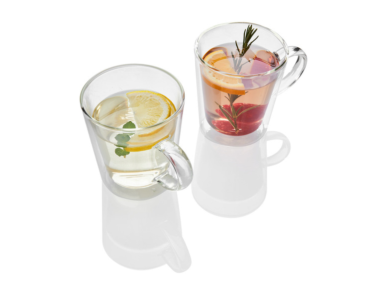 Dva poháre s rukoväťou naplnené čajom s citrónom, mätou a malinami.