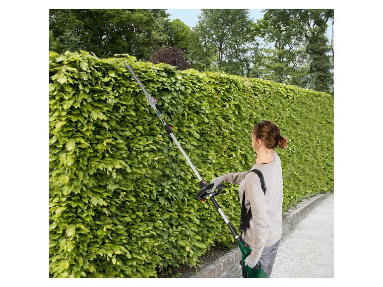 Žena používa dlhé STIHL nožnice na živý plot na orezávanie vysokého živého plotu.
