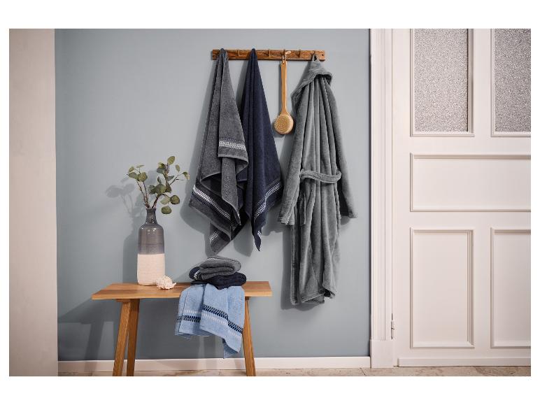 Kúpeľňa s uterákmi, županom a drevenou lavicou s vázou a mušľou.