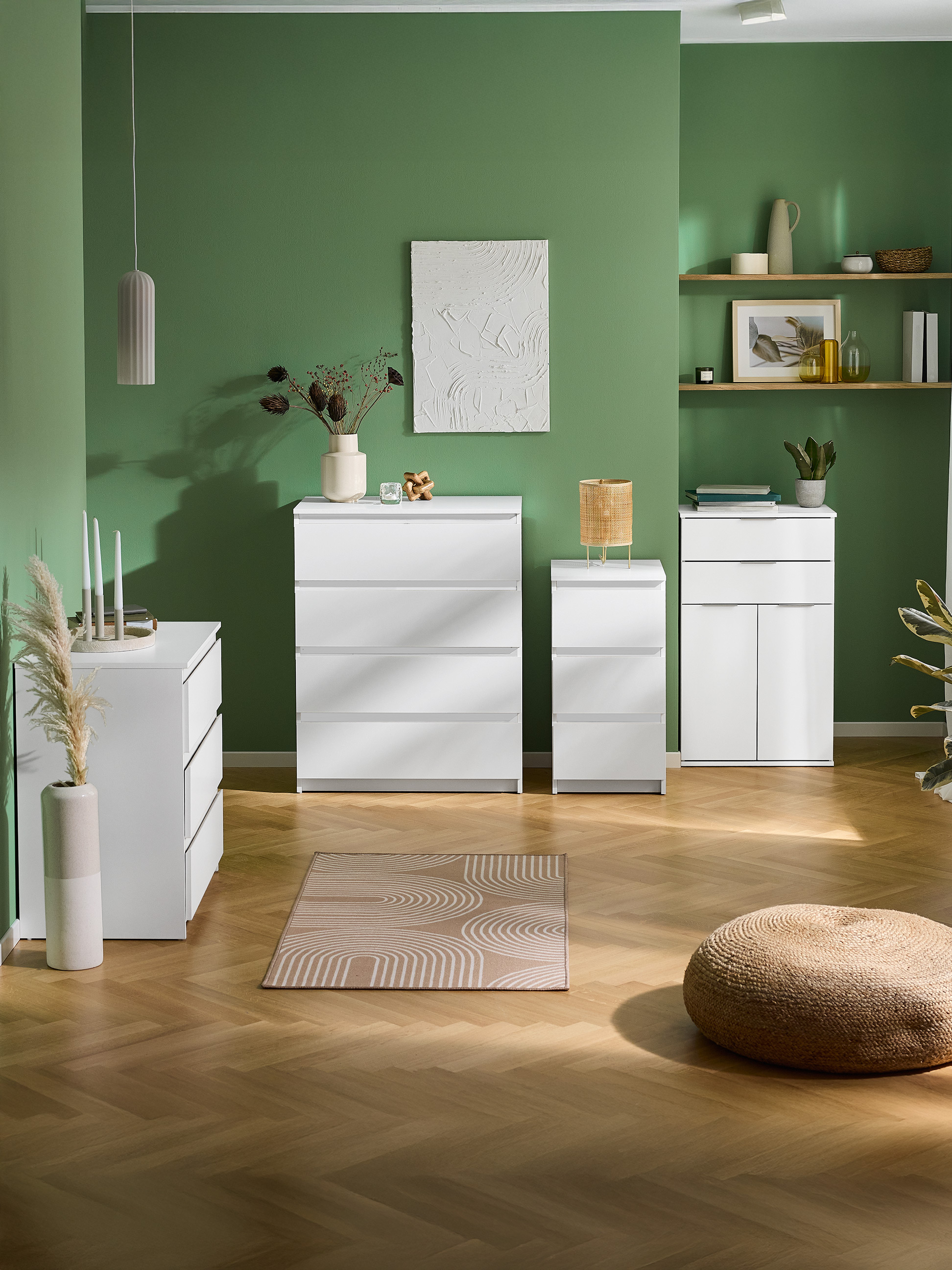 Biele komody a skrinky v zelenej izbe s drevenou podlahou a kobercom.