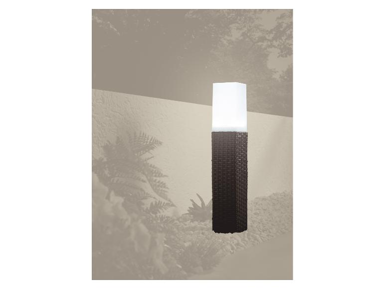 Záhradná lampa v tvare pleteného stĺpa osvetľujúca štrkovú cestu.