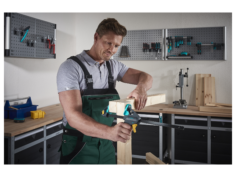 Muž v dielni používa svorku Wolfcraft na spojenie drevených dielov.