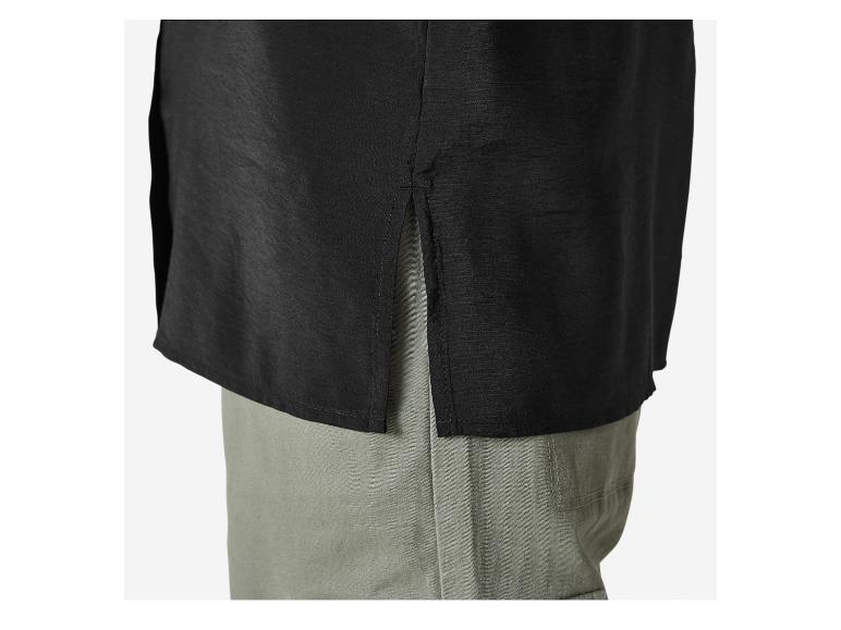 Čierne tričko so štrbinou na boku v kombinácii so zelenými nohavicami.