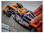Ruka vkladá figúrku do čierno-oranžového pretekárskeho auta LEGO McLaren.