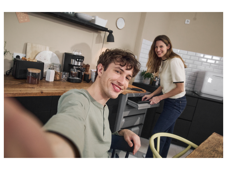 Pár v modernej kuchyni so zabudovanými spotrebičmi.