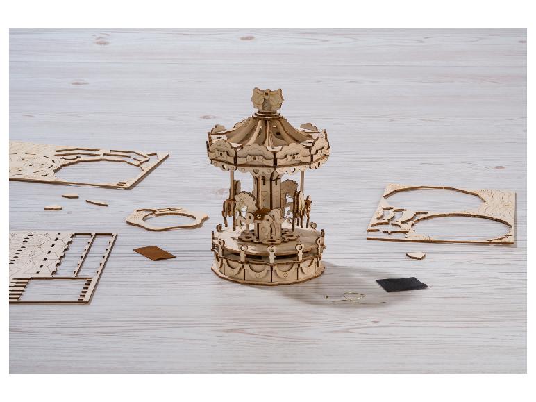 Zmontovaný drevený kolotoč a diely skladačky na drevenom stole.