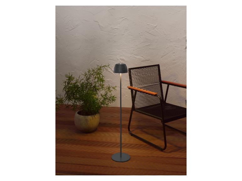 Moderná stojaca lampa a črepníková rastlina na drevenej terase so stoličkou.