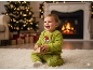 Šťastné dieťa v pyžame Grinch drží darček pred vianočným stromčekom a krbom.
