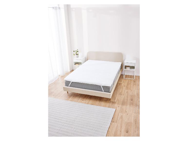 Biely chránič matraca na posteli v minimalistickej spálni.