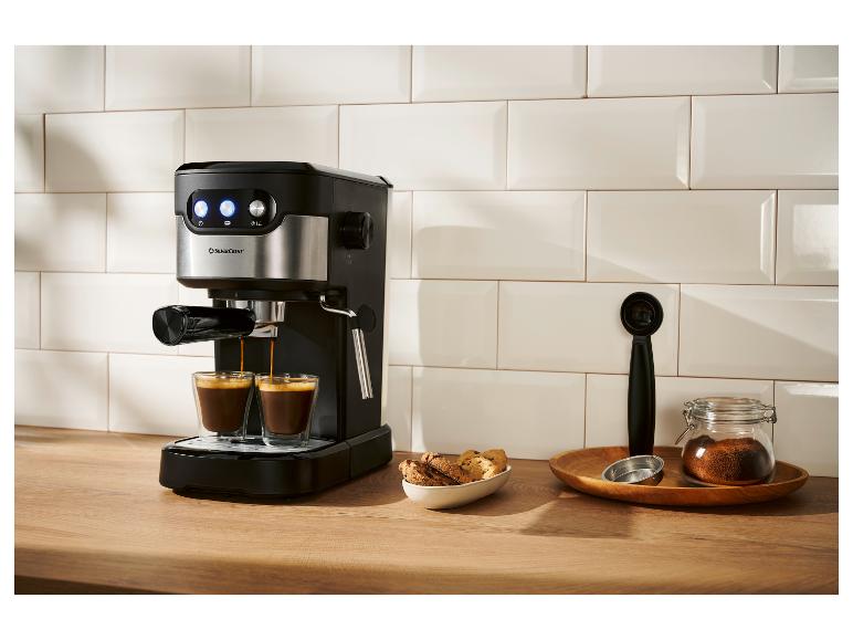 Čierny a strieborný kávovar na espresso pripravuje dve šálky kávy v modernej kuchyni.