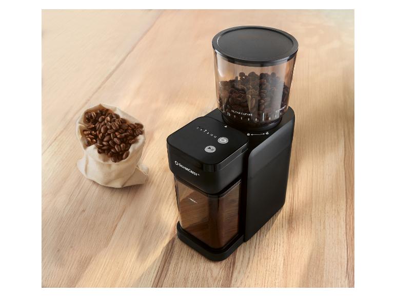 Čierny mlynček na kávu SILVERCREST s priehľadnou nádobou na zrná a vreckom kávových zŕn.