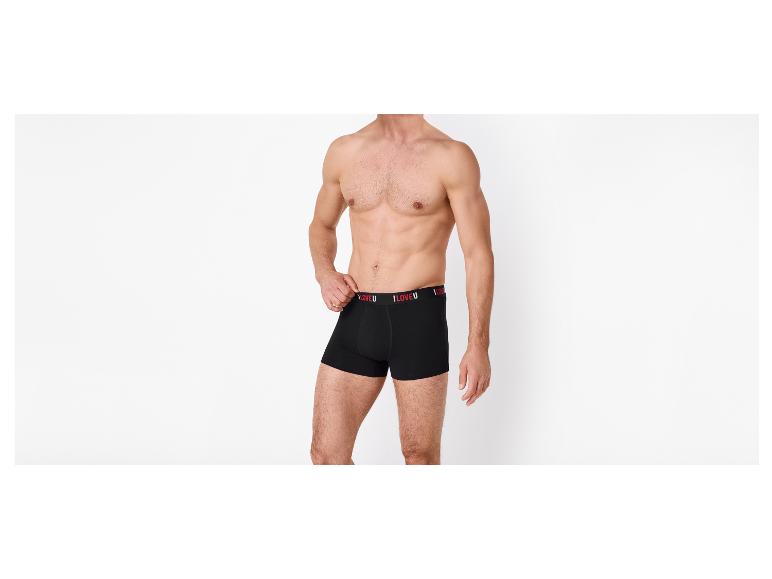 Muž bez trička v čiernych boxerkách s nápisom „I LOVE U“ na páse.