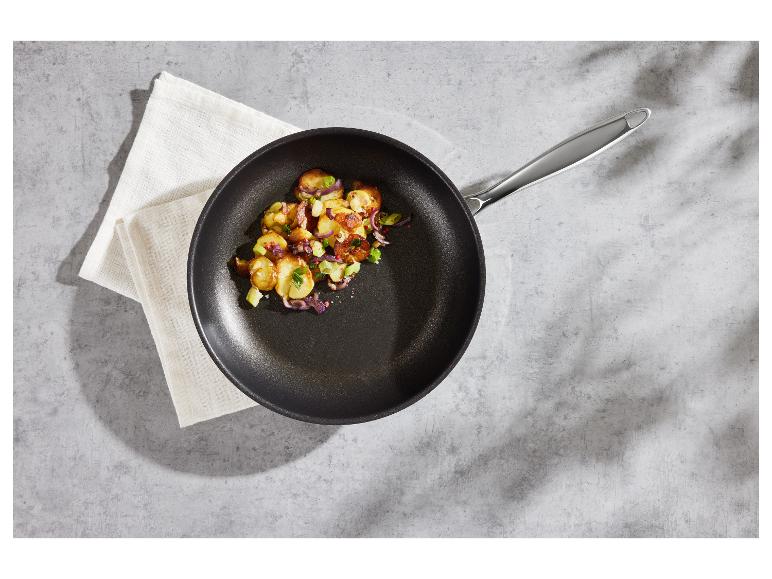 Panvica s pečenými zemiakmi a zeleninou na sivom povrchu.