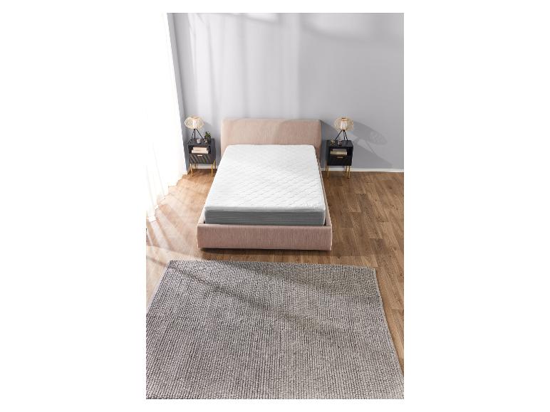 Ružová posteľ s bielym matracom a sivým kobercom.