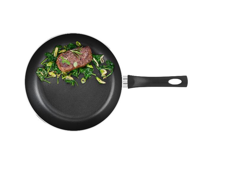 Steak s opečenou špenátom na čiernej panvici.