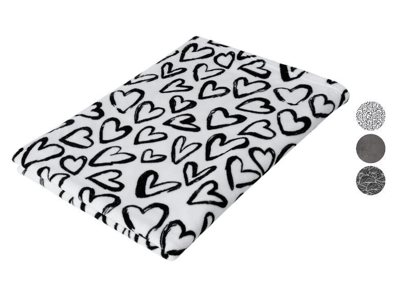 Biela deka s čiernymi srdiečkami a tromi okrúhlymi vzorkami.