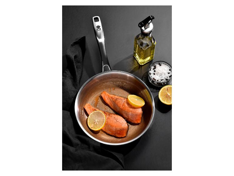 Panvica s dvoma kúskami lososa, citrónom, soľou a korením na čiernom pozadí.