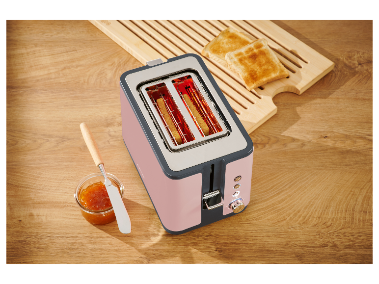 Ružový dvojpriehradový hriankovač s opečeným chlebom na drevenej doske.