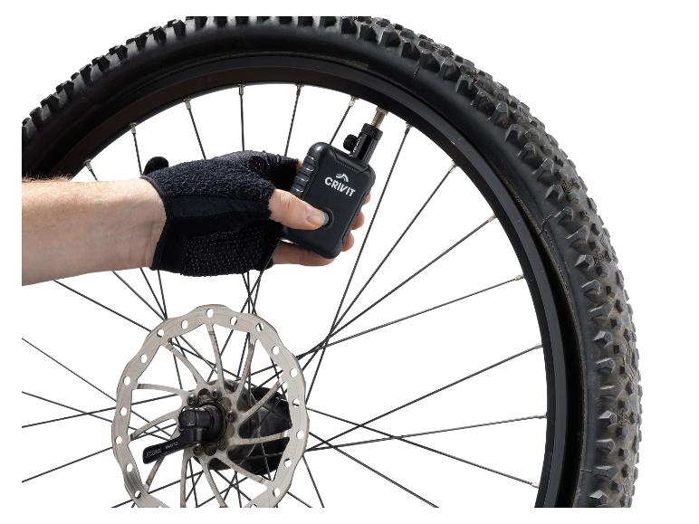 Ruka v rukavici nafukuje pneumatiku bicykla Crivit digitálnou vzduchovou pumpou.