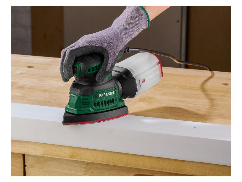Osoba brúsi bielu dosku delta brúskou na drevenom pracovnom stole.