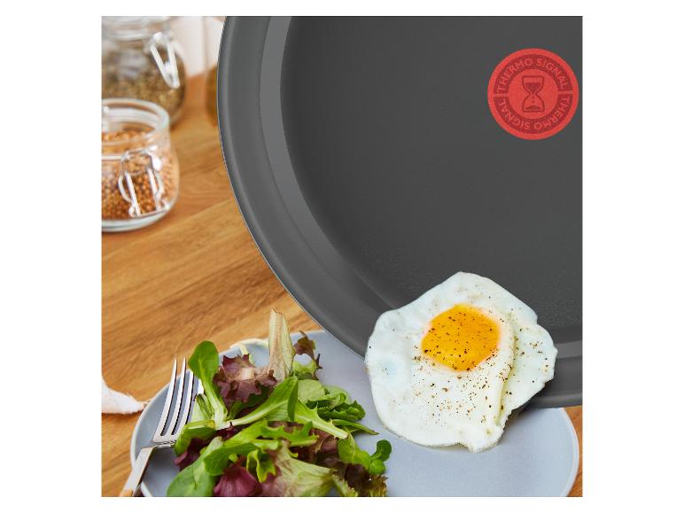 Panvica Tefal s volským okom a šalátom na tanieri, korenie v pozadí.