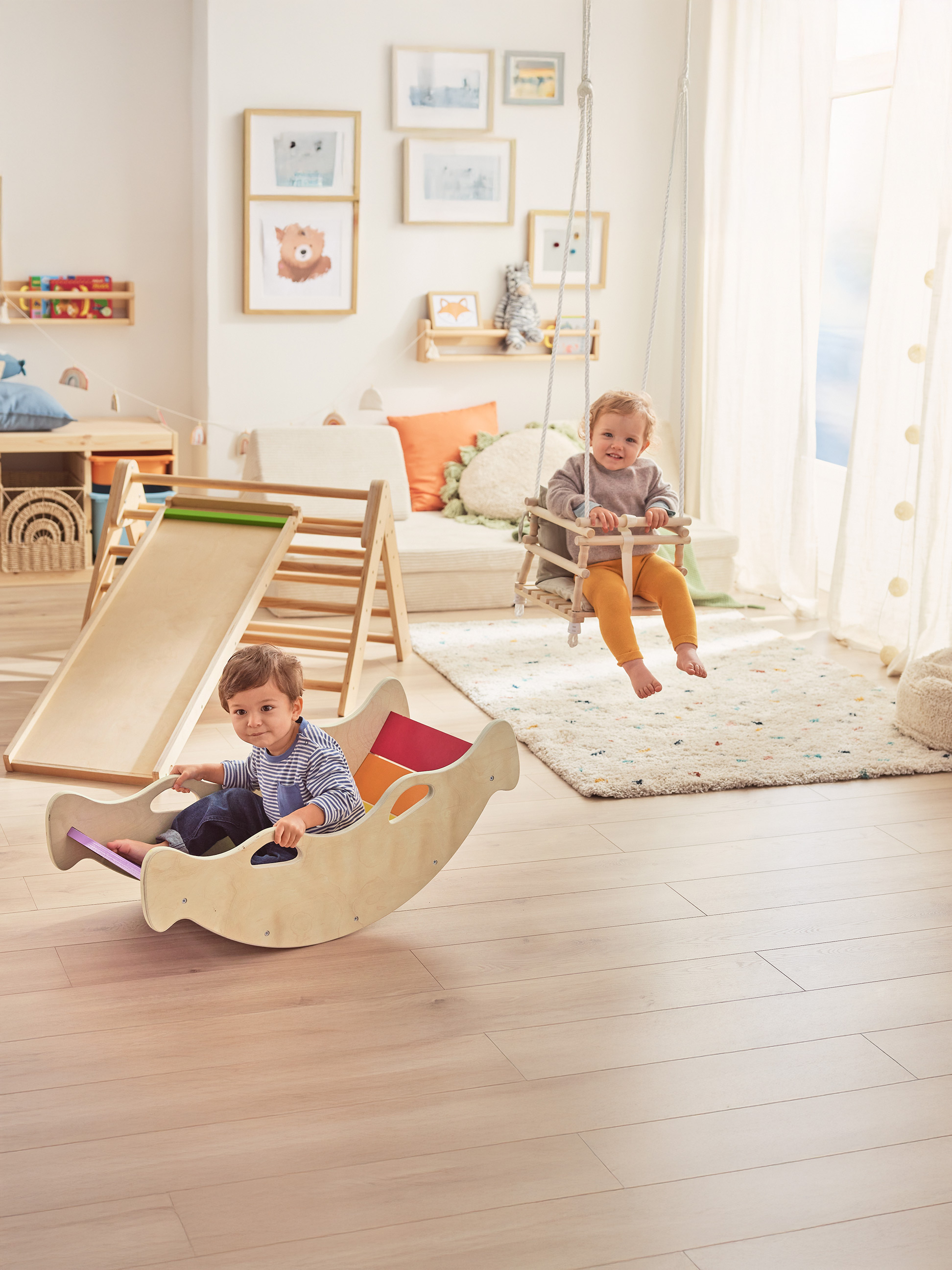 Dve šťastné batoľatá sa hrajú s drevenými hračkami vo svetlej detskej izbe.