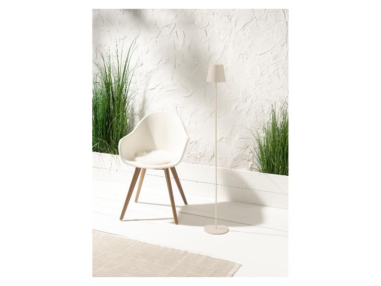 Biela dizajnová stolička, stojaca lampa a zelené rastliny v minimalistickom interiéri.
