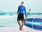 Muž s paddleboardom Mistral a oblečením v rovnakom štýle.