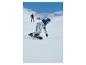 Snowboardista v vzorovaných nohaviciach a svetlomodrej bunde klesá po zasneženom svahu.