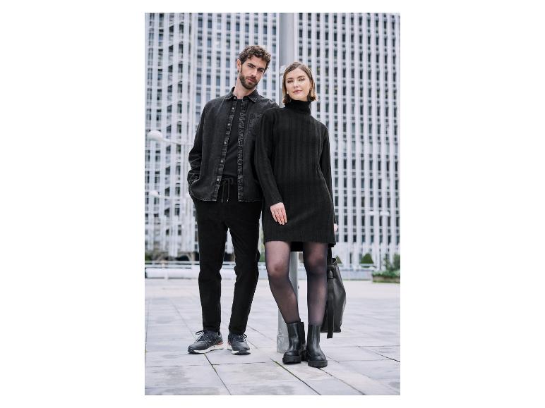 Pár v elegantnom čiernom oblečení pred modernými budovami.