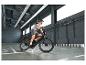 Muž v prilbe a veste jazdí na čiernom elektrickom bicykli v hale.