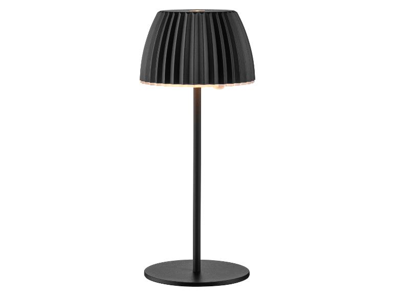 Čierna stolná lampa s plisovaným tienidlom a okrúhlou základňou, osvetlená.