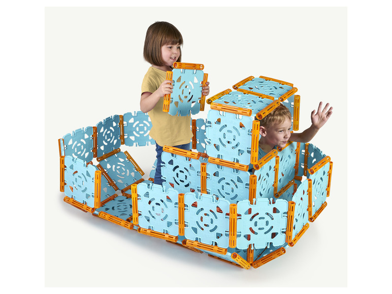 Dve deti sa hrajú s modrými a oranžovými kockami a stavajú vežu.