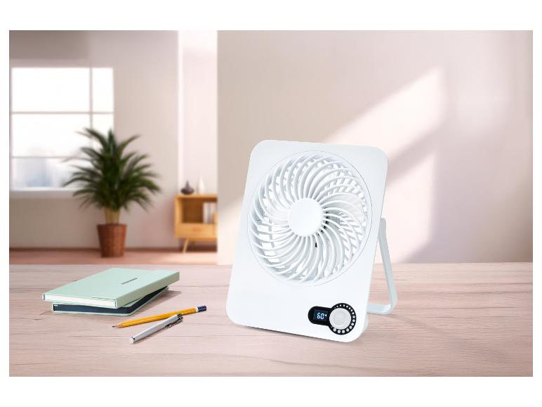 Biely stolný ventilátor s digitálnym displejom 60° na drevenom stole s poznámkovými blokmi a perami.