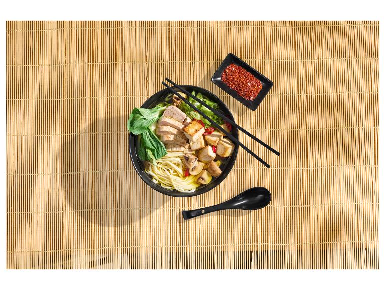 Miska ramenu s kuracím mäsom, tofu, hubami a bok choy na bambusovej podložke.