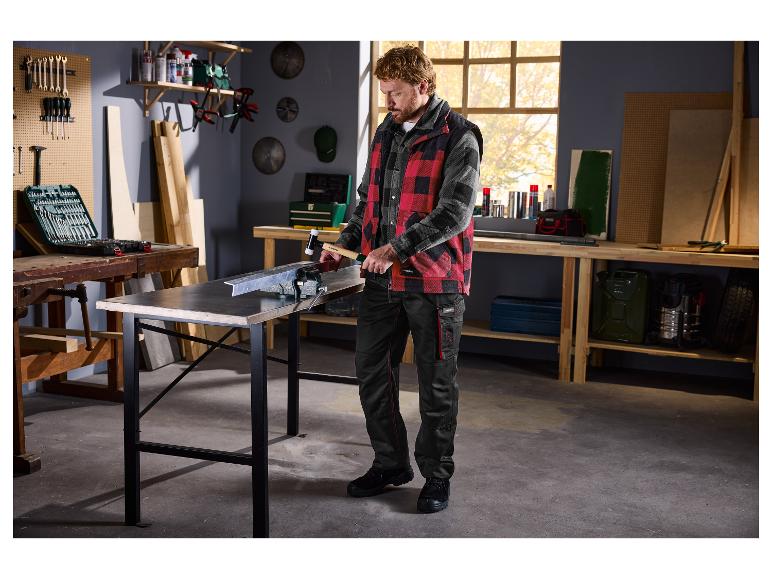 Muž v dielni používa gumené kladivo na kovový kus upnutý vo zveráku.