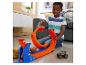 Usmiaty chlapec sa hrá so súpravou dráhy Hot Wheels Monster Trucks a autom.