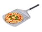 Čerstvo upečená pizza s bazalkou na kovovej lopate na pizzu.