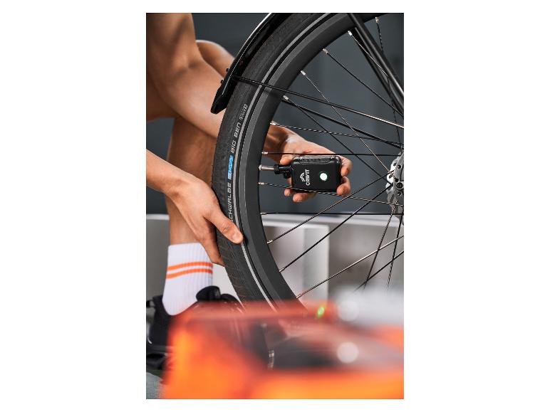 Osoba nafukuje pneumatiku bicykla prenosnou vzduchovou pumpou.