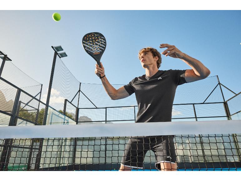 Muž hrajúci padel, držiaci padelovú raketu, s tenisovou loptičkou vo vzduchu.