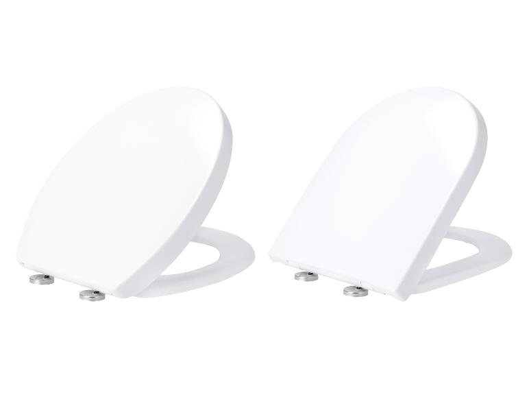 Dve biele, oválne záchodové dosky na bielom pozadí