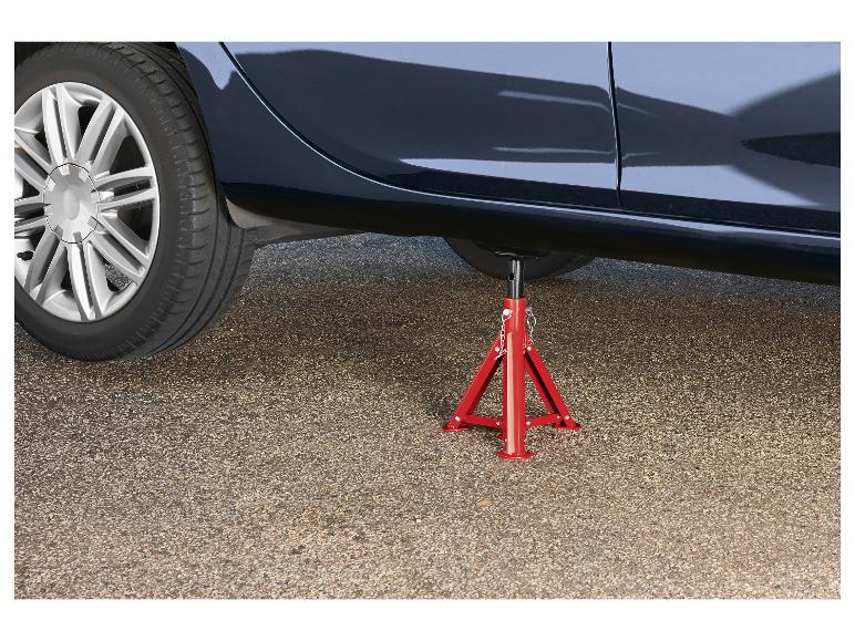 Auto podopreté červeným stojanom na zdvihák na asfaltovom povrchu.
